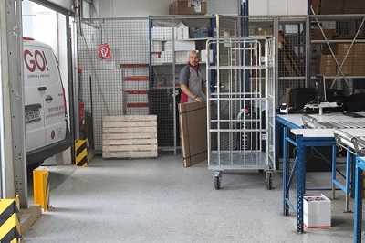 GO! Kurier lädt die Waren aus dem GO! Transporter in den passenden Rollcontainer für die Station
